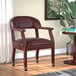 A red vinyl Boss captain's chair with casters next to a table with a plant.