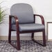 A gray Boss side chair with a mahogany frame next to a plant.