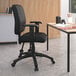 A black Boss office chair with adjustable arms at a desk with a laptop.