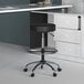 A Boss black vinyl drafting stool under a white desk.