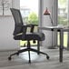 A Boss black mesh task chair next to a desk.