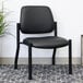 A black Boss armless guest chair with metal legs next to a plant.