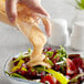 A hand pouring AAK Select Thousand Island Dressing into a bowl of salad.