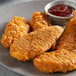 A plate of Brakebush Gold'N'Spice breaded chicken tenderloins with sauce.