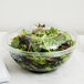 A clear plastic dome lid on a bowl of salad.