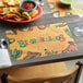 A table with a plate of chips and a Choice Mexican themed paper placemat.