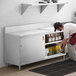 A man putting food in a stainless steel enclosed base cabinet on a Regency stainless steel table.