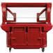 A red food cart with a clear glass top.