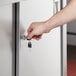 A hand opening a stainless steel sliding door on a Regency enclosed base table.