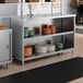 A stainless steel dish cabinet with an adjustable midshelf, holding stacks of plates and bowls.