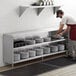 A man putting plates on a Regency stainless steel dish cabinet shelf.