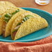 A group of Mission yellow corn hard tacos on a blue plate.