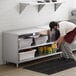 A man putting food in a container on a Regency stainless steel table with a shelf.