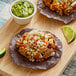 Two tacos with meat and vegetables on a wood surface with a lime wedge.