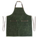 A Hardmill olive waxed canvas apron with brown straps on a table.