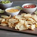 A white bowl of Mission tortilla chips with a bowl of salsa on a table.