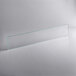A clear rectangular glass shelf with green lines on a white surface.