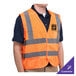A person wearing a Cordova orange high visibility safety vest with customizable features.