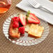 A Fineline clear plastic plate with cheese, strawberries, and crackers.