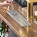 A stainless steel surface mount beer drip tray with a built-in glass rinser on a bar counter.