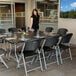 A woman standing at a table with a Lifetime Classic black folding chair.