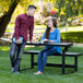 A man and a woman sitting at a Lifetime convertible bench reading a book.