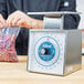 A person using an Edlund mechanical portion scale to weigh a bag of beans.