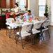 A family of four sitting at a Lifetime white plastic folding table.