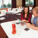 A man and a woman sitting at a white Lifetime plastic folding table with a glass on it.