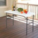 A Lifetime white plastic folding table on a patio with bowls of salad, peppers, and tomatoes.