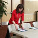 A woman in a red shirt standing at an almond Lifetime plastic folding table.