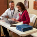 A man and woman using laptops at a white Lifetime seminar table.