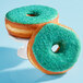 A close up of a donut with Adourne Light Green sanding sugar.