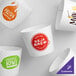 A group of white coffee cups with different designs in customizable embossed coffee cup sleeves.