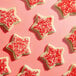 A group of star-shaped sugar cookies topped with fine red sanding sugar.