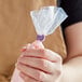 A person holding a Wilton purple plastic bag with a plastic bag inside.
