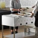 A woman serving food to a man from a ServIt electric steam table.