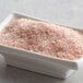 A bowl of Regal medium grain pink Himalayan salt on a table.