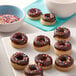 A plate of chocolate donuts with sprinkles.