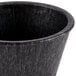 A close up of a black polyethylene ramekin with a handle.