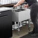 A woman standing in front of a Regency underbar sink in a professional kitchen.