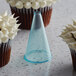 A frosted cupcake with a cone on top.