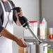 A man using a Galaxy light-duty hand-held immersion blender to mix food.