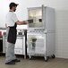 A man in a black apron standing in front of a Beverage-Air double stacked glass door refrigerator.