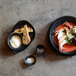 A plate of food with shrimp and bread with a bowl of white sauce and a bowl of white powder on it.