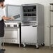 A man in a black apron and gloves opening a Beverage-Air undercounter freezer with left hinged doors.