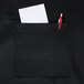 A black Chef Revival bib apron with a pocket holding a pen and paper.