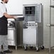 A man in a black apron using a Beverage-Air undercounter freezer with casters.