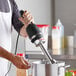 A man using a Galaxy light-duty immersion blender to make food in a professional kitchen.