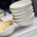 A stack of white Front of the House porcelain ramekins filled with fruit and candy.